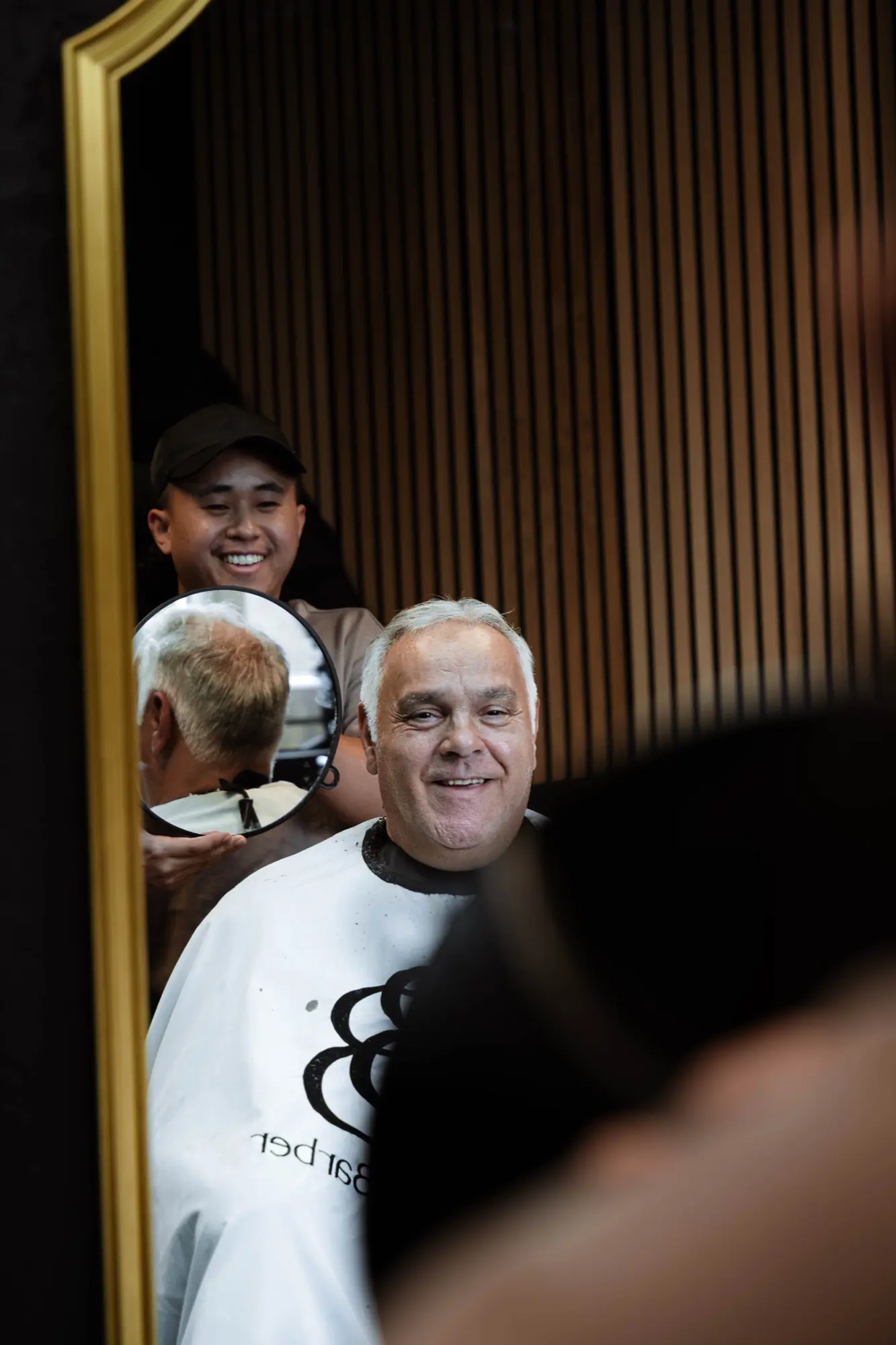 Sourires dans le miroir doré du salon Boonk Barber